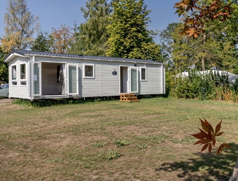 Witte stacaravan op een groene jaarplaats op de camping.